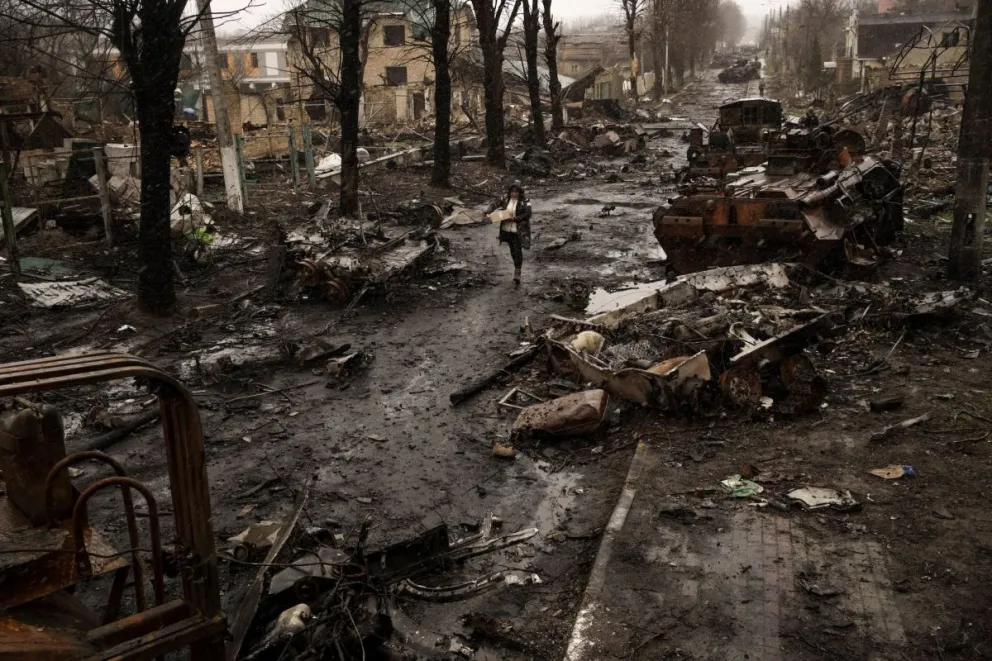 Una mujer camina entre los tanques rusos destruidos en Bucha, en las afueras de Kiev, Ucrania, el 3 de abril de 2022 // Foto de Rodrigo Abd (AP)