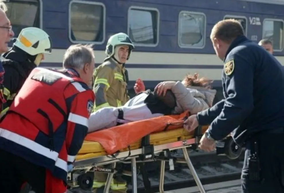 Efectivos de bomberos asisten a heridos en la estación ferroviaria de Dnipro tras el ataque con drones que ocasionó 14 muertos y otros 14 heridos, algunos de ellos graves.